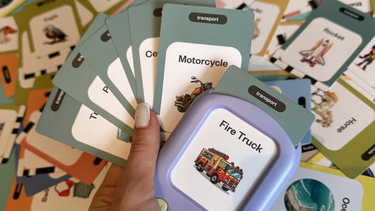 A hand holding SmartKiddo Pocket Vocab learning toy and vocabulary flashcards, illustrating how words shape a child’s understanding of the world
